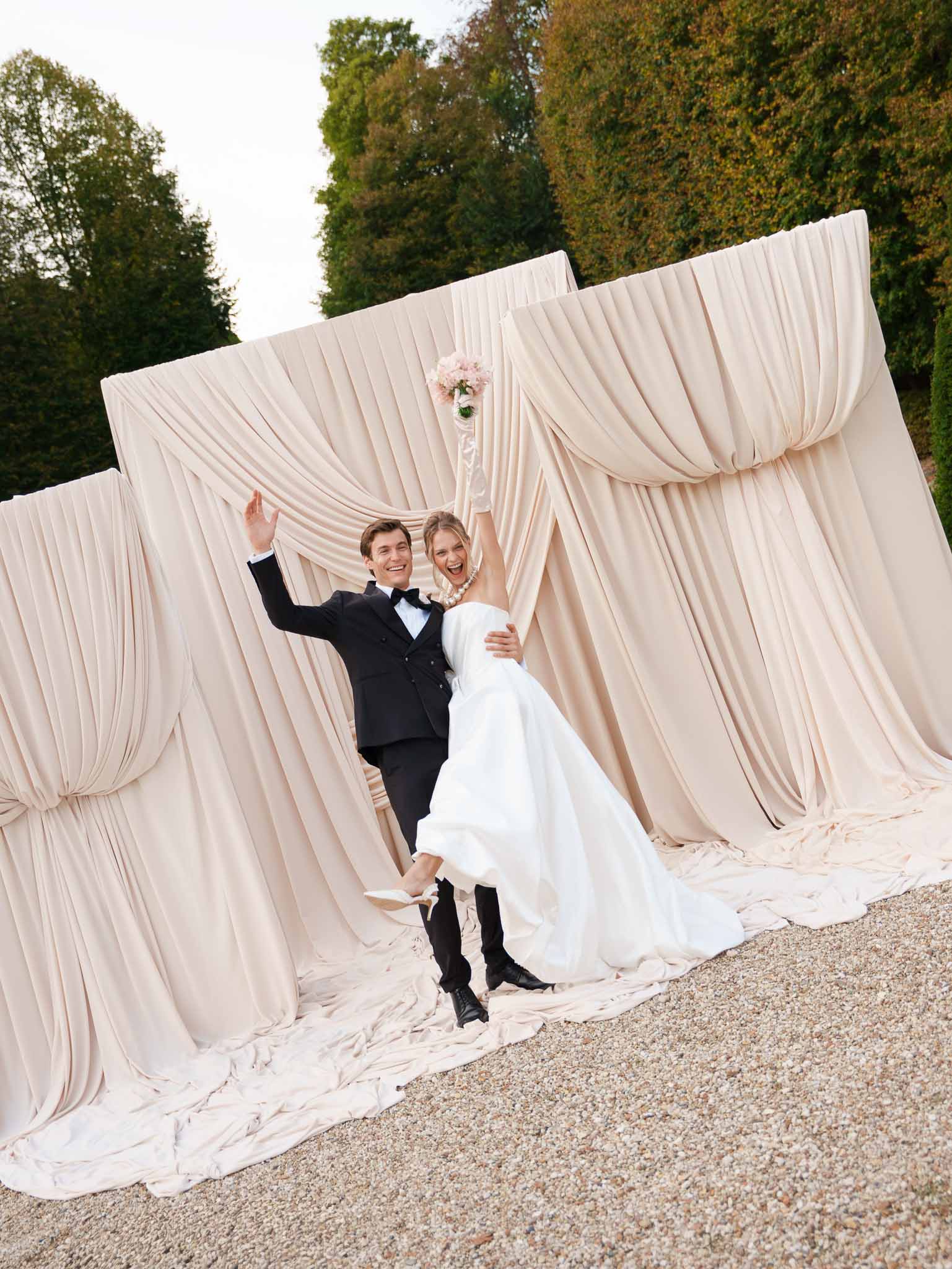 Couple standing beneath draped fabric ceremony arch