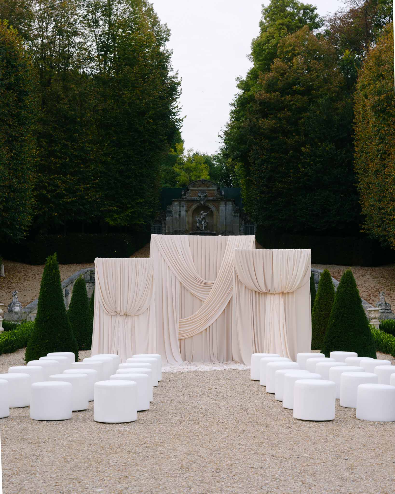 Outdoor ceremony with circular chair arrangement and draped arch at Chateau de Villette