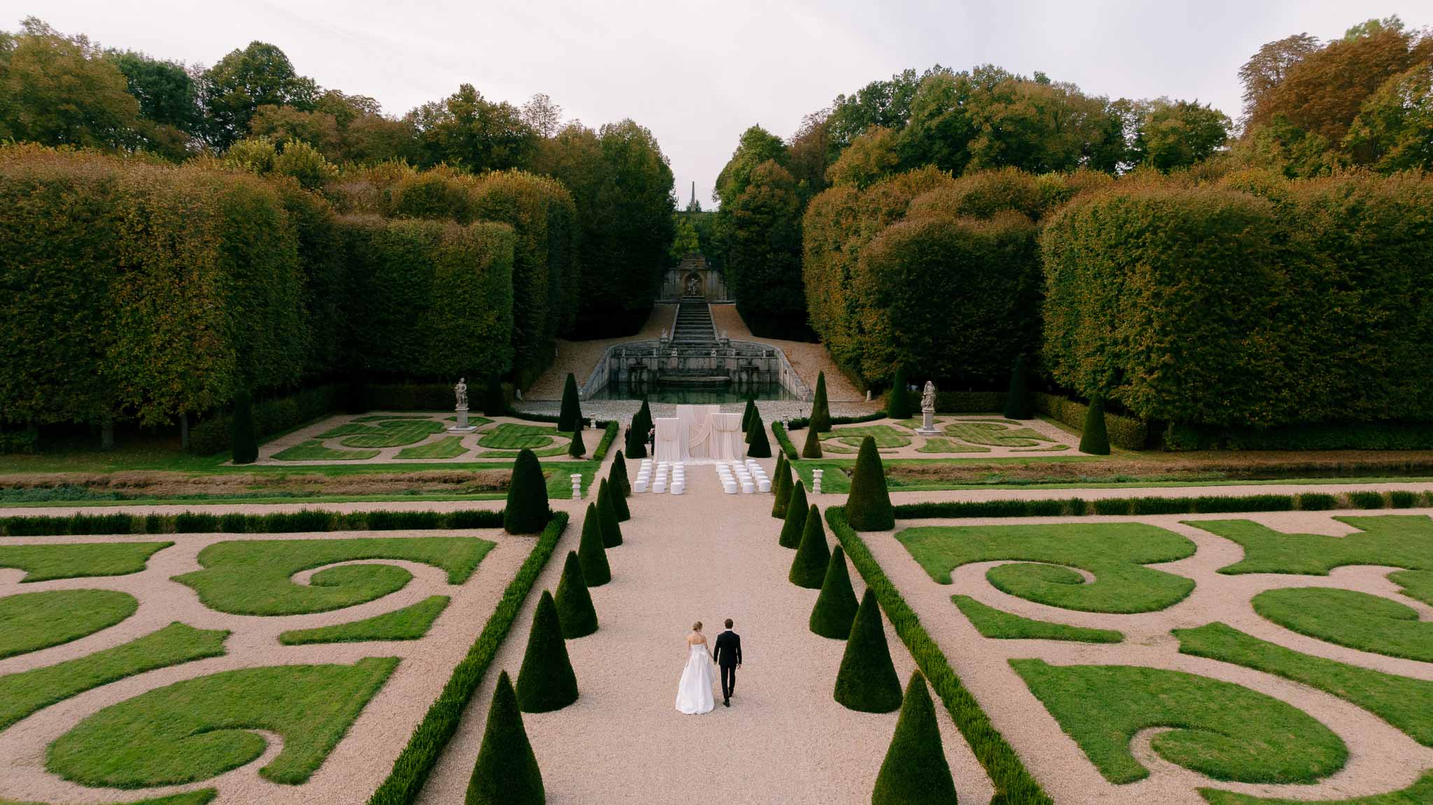 Wide landscape shot of couple walking through Chateau de Villette gardens