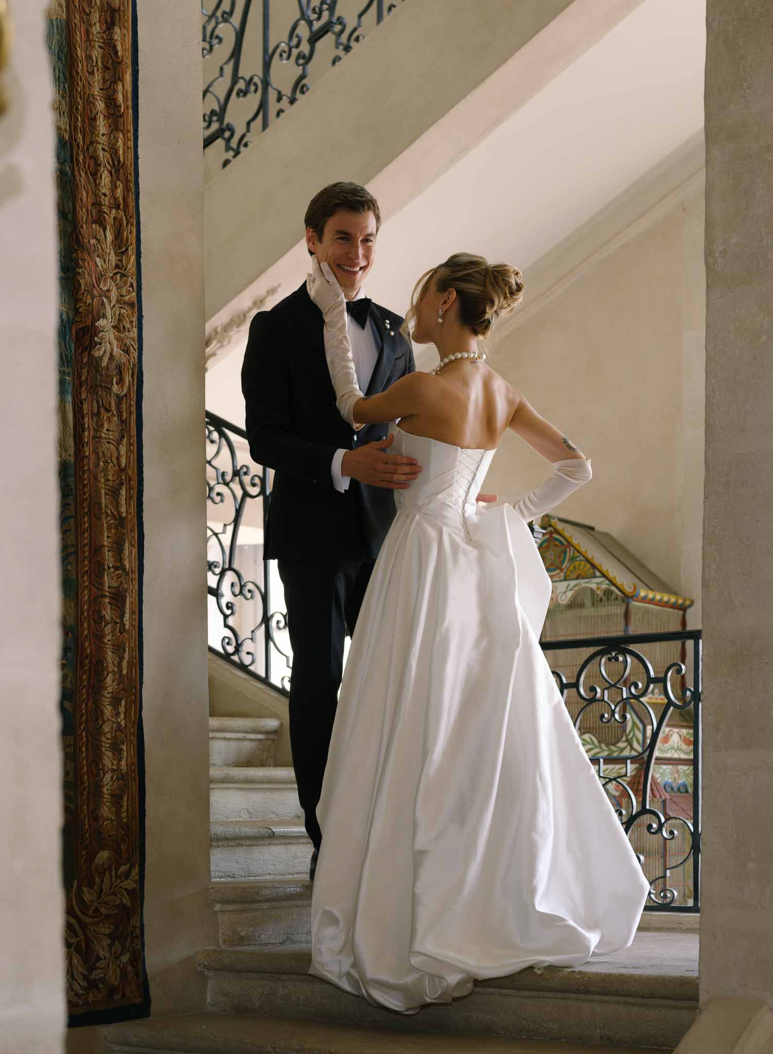 Couple hugging on the grand interior staircase of Chateau de Villette