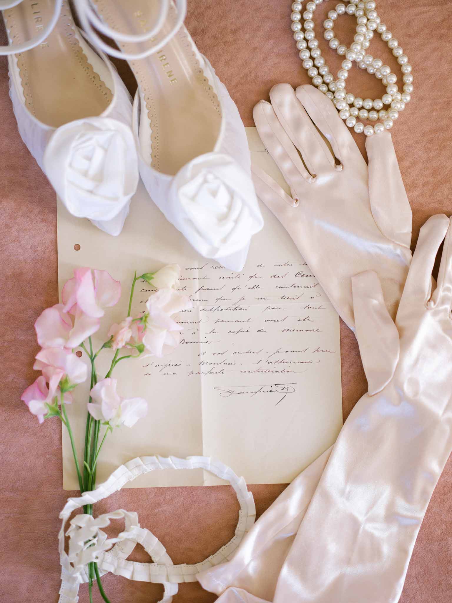 Flatlay of bridal accessories including pointed shoes, long gloves, and jewellery