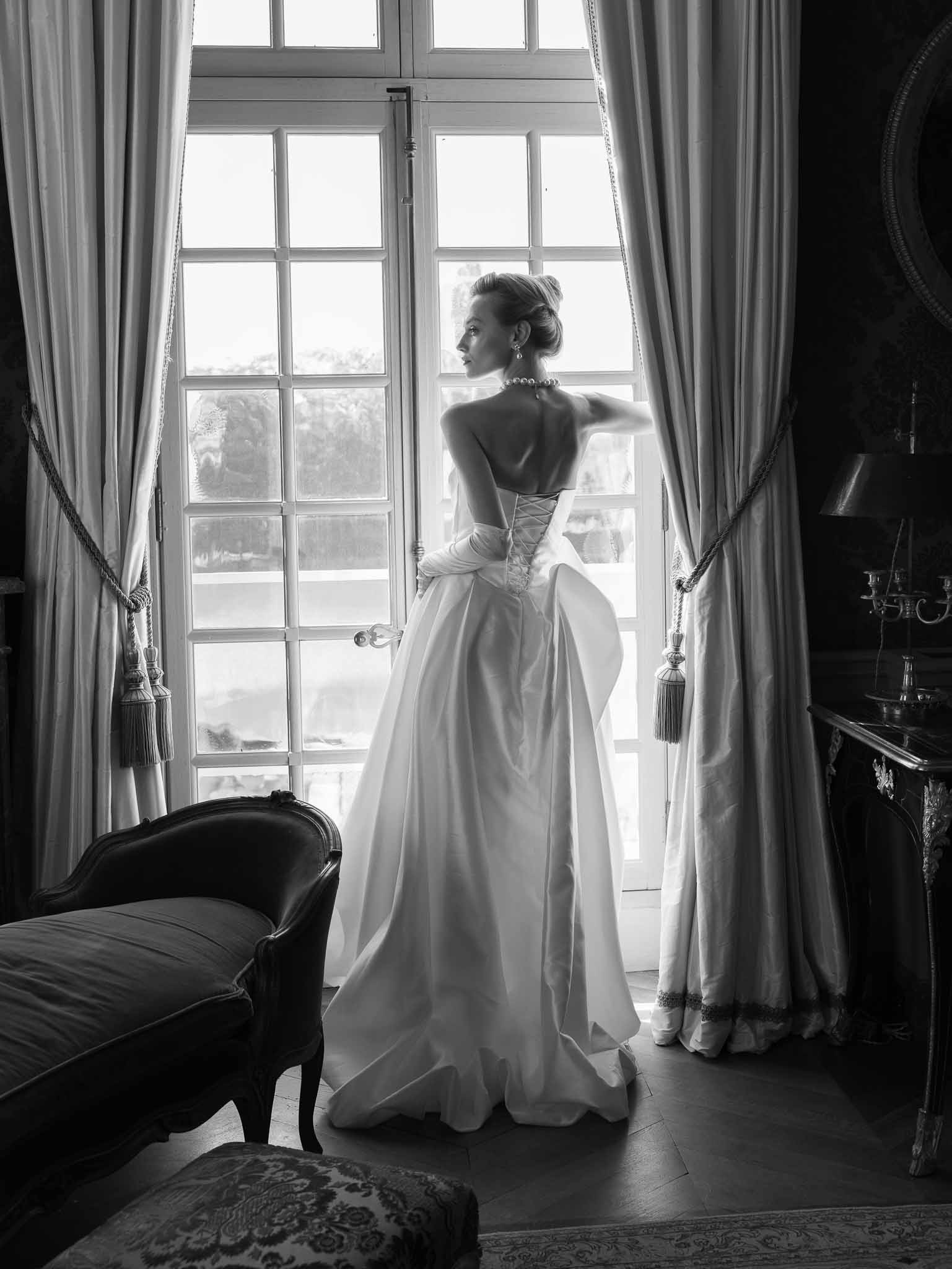 Bride gazing out through the chateau window during preparations
