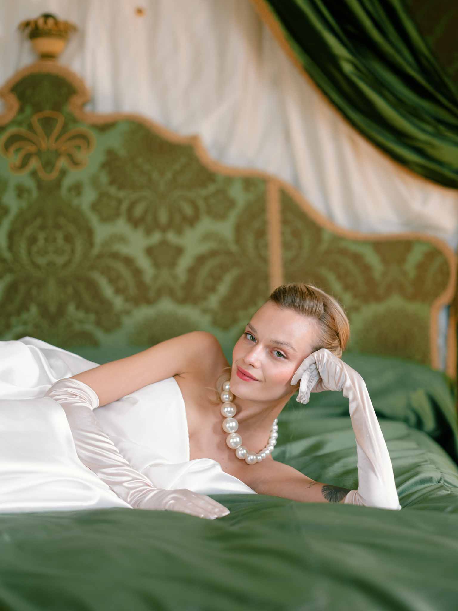 Close-up portrait of bride reclining on vintage bed
