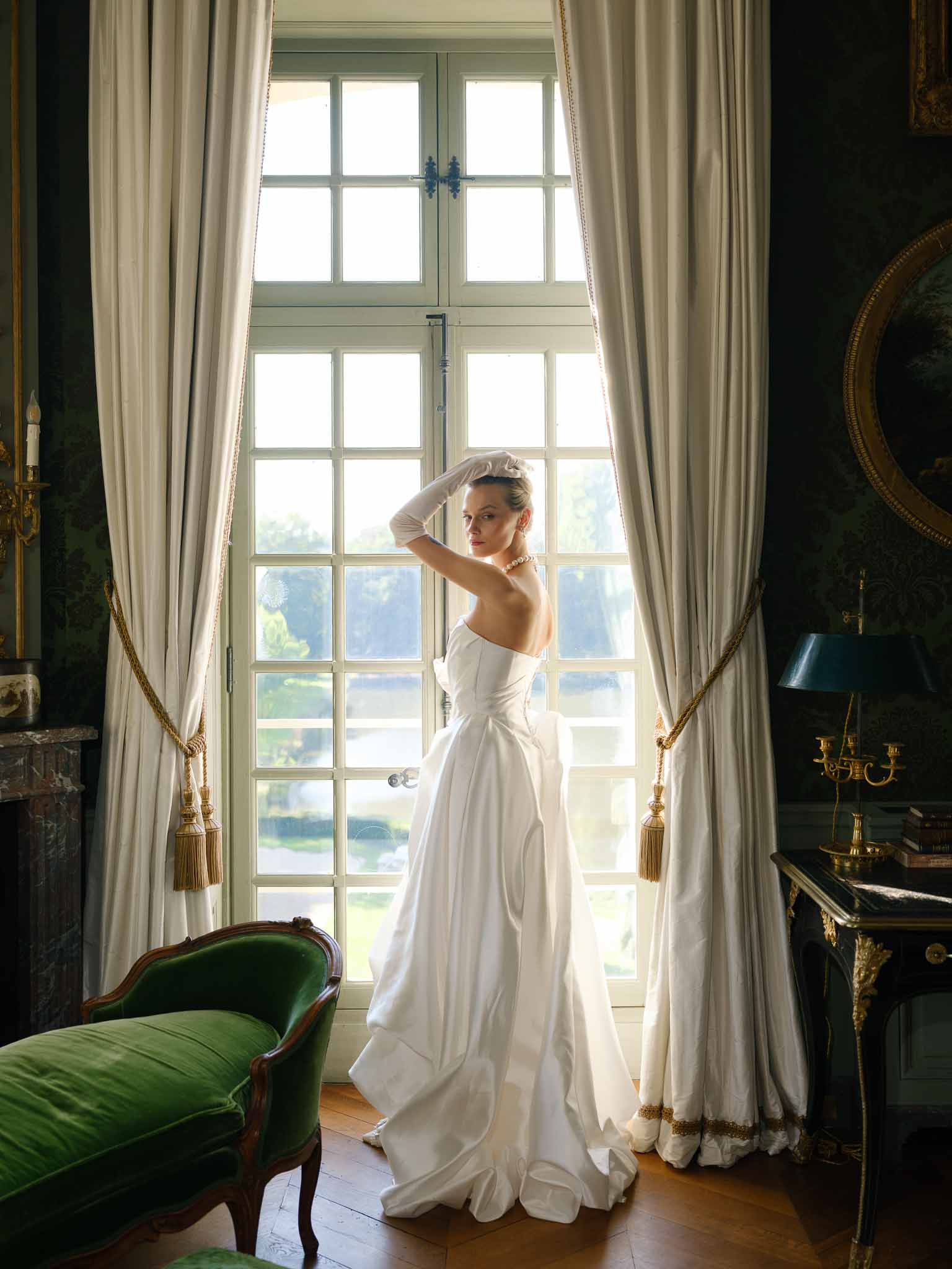 Bride standing by a tall window in the chateau's period room