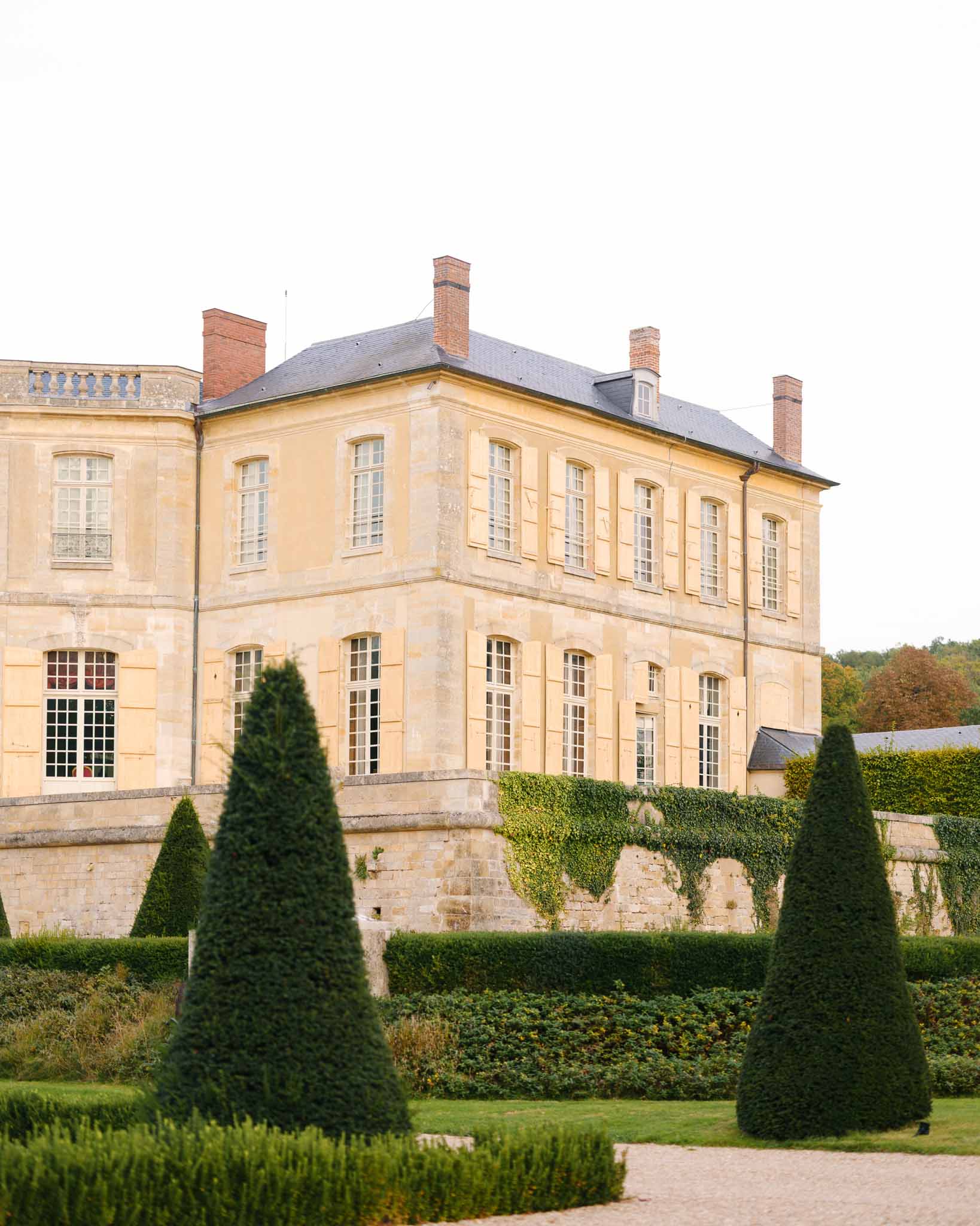 Golden hour light filtering through trees on the Chateau de Villette grounds