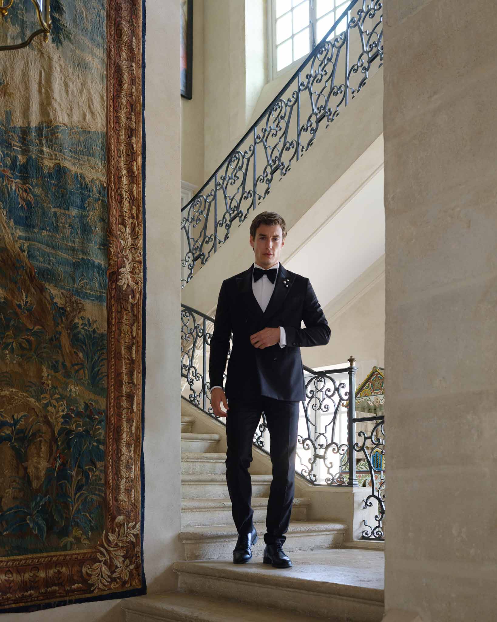 Groom in tuxedo posing on the grand staircase of Chateau de Villette