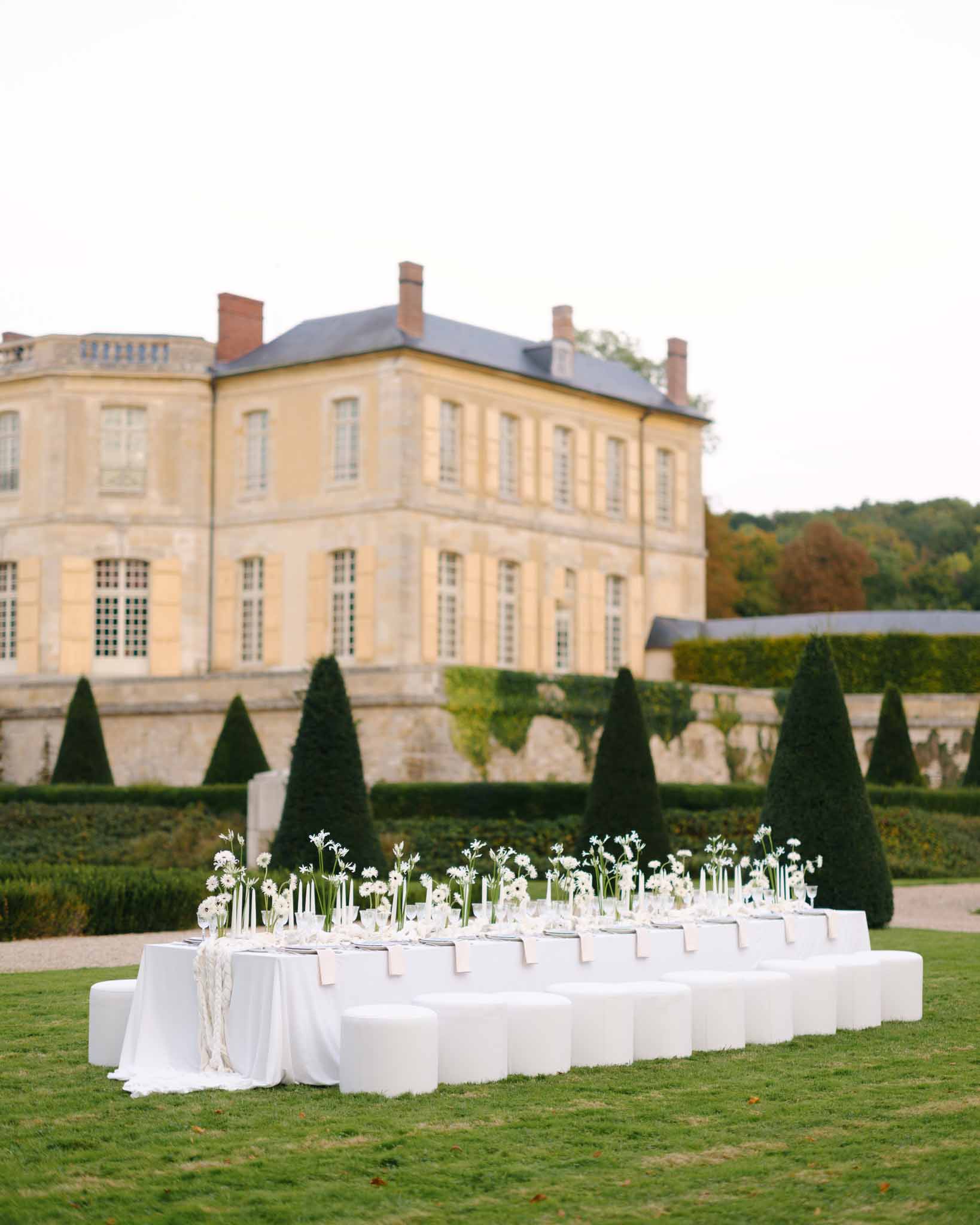 Round reception table arrangement with white chairs at the chateau